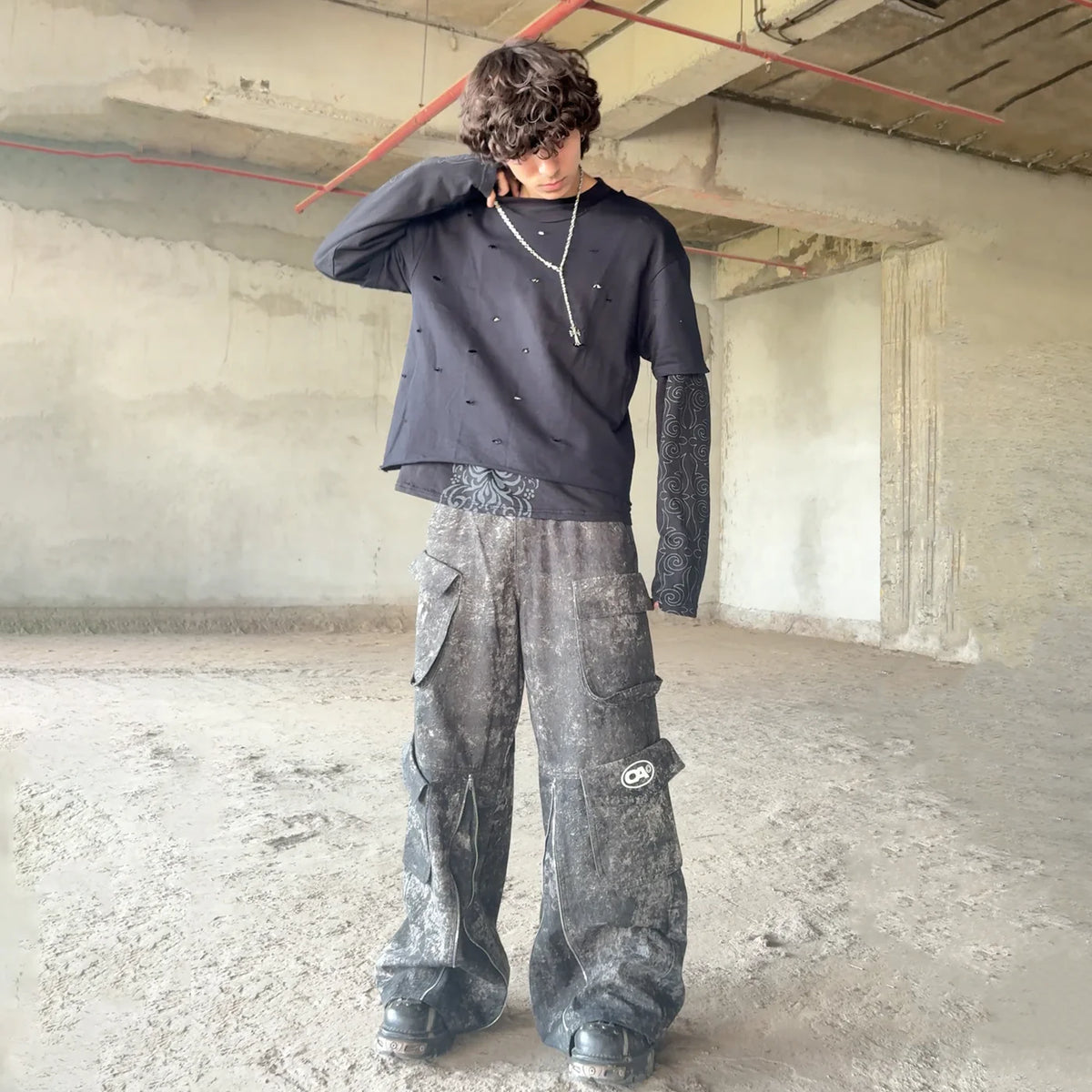 Dark charcoal camo cargo pants on model, wide legs with flap pockets and stitching.