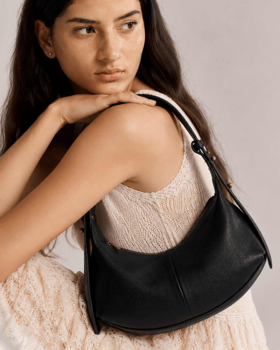 Black shoulder hobo bag worn over arm, with zip pocket detail