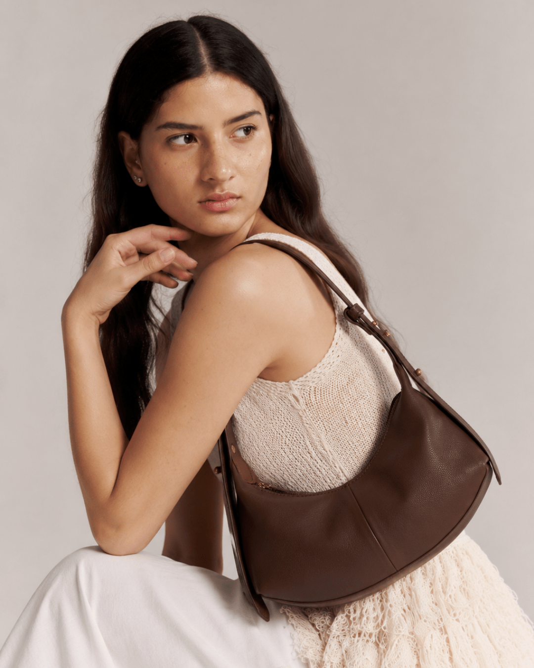 Brown hobo shoulder bag with single strap worn over shoulder; smooth leather-look body.