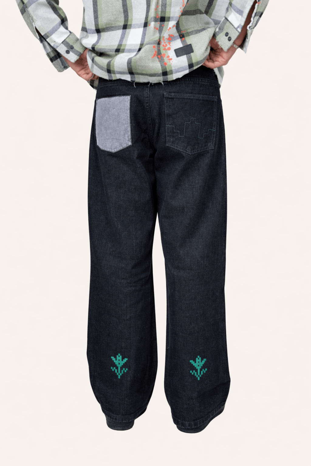 Black denim jeans with wide legs, front patch pockets, and green embroidered motifs