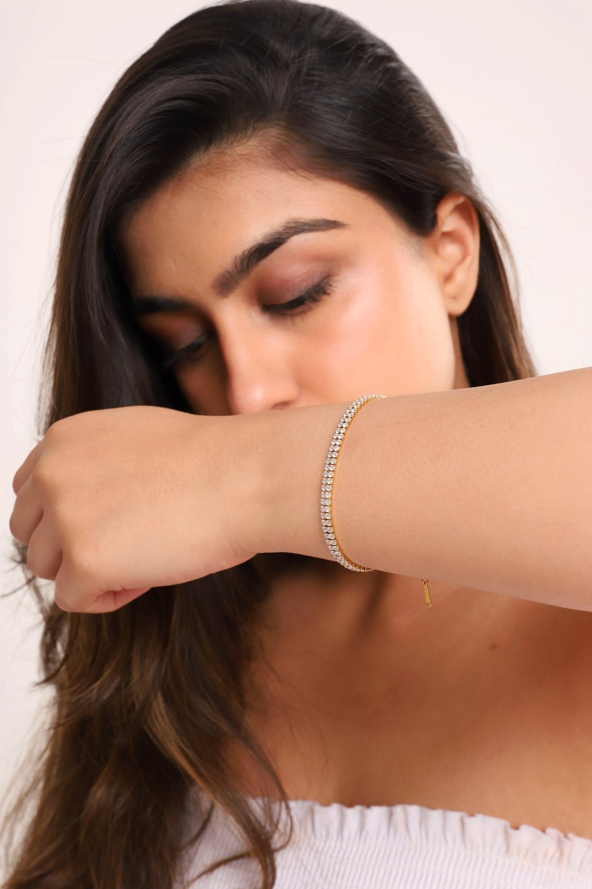 Gold tennis bracelet with clear stones, worn on forearm