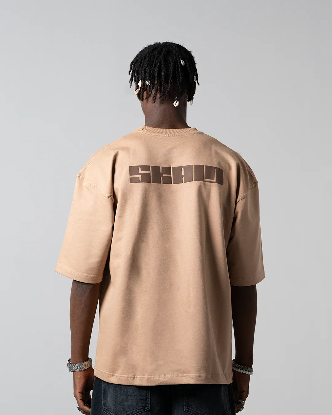 Beige crewneck T-shirt with large back logo graphic, short sleeves.