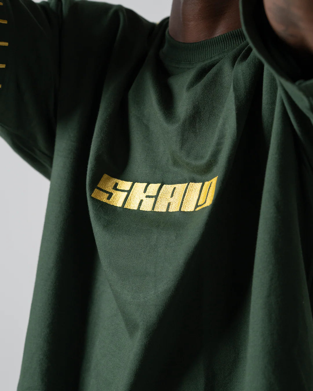 Green graphic T-shirt close-up of yellow SHAWN chest logo