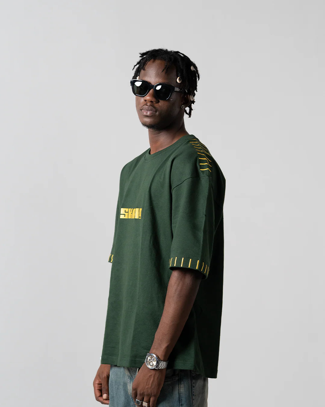 Green graphic T-shirt with yellow logo patch and striped sleeve cuffs