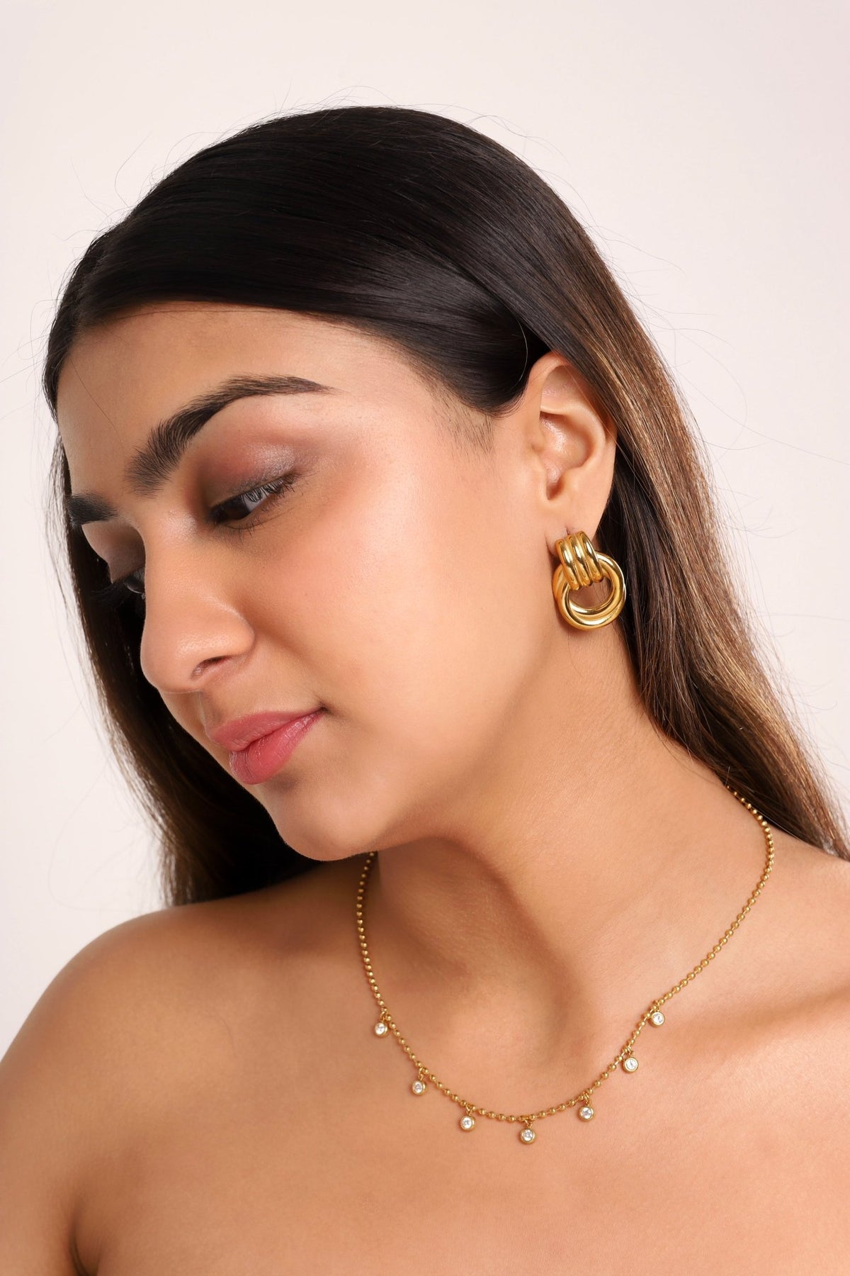 Gold-tone layered hoop earrings with stacked coil bands, worn on ear