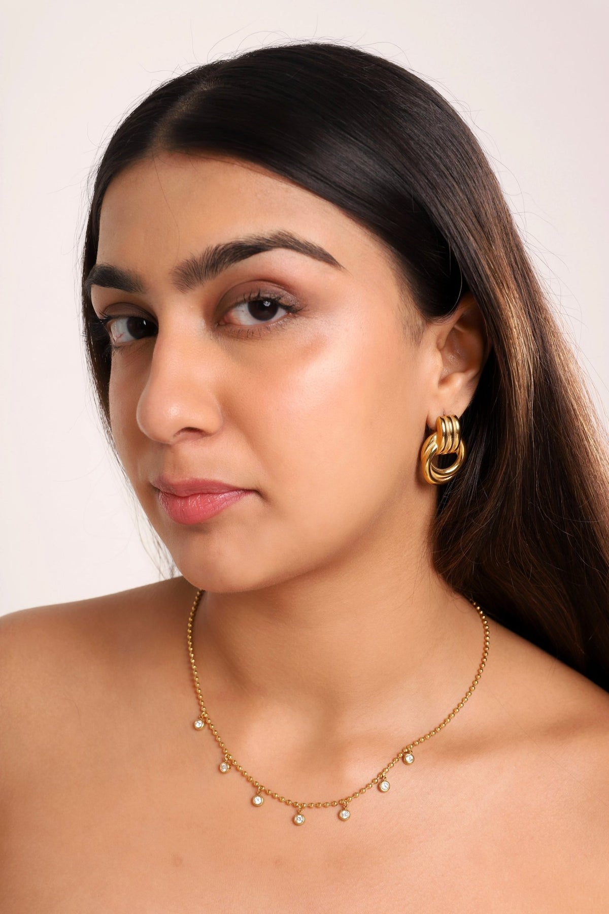 Gold-tone layered hoop earrings with stacked coil bands, worn on ear