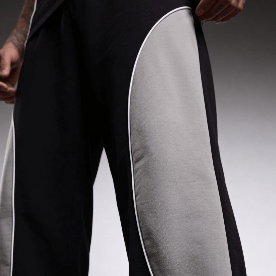 Baggy sweatpants close-up: black legs with light gray side panel trim