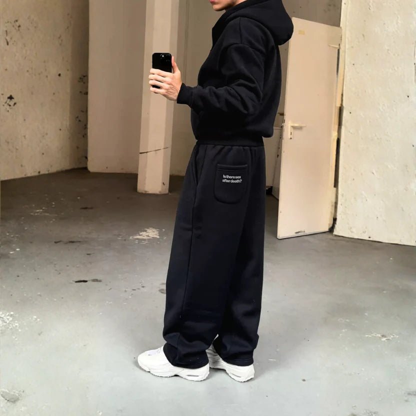 Black sweatpants with relaxed fit, drawstring waist, and logo patch on back pocket.