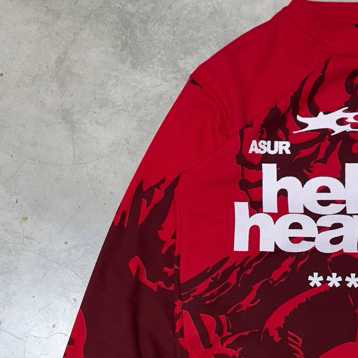 Red long-sleeve waffle knit top angled view with “hell & heaven” text partially visible