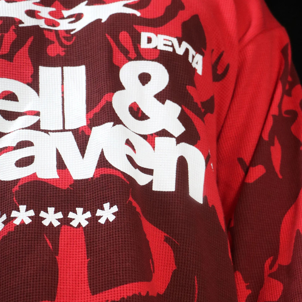 Red long-sleeve waffle knit top with bold “DEVTA” logo and large white “&” text