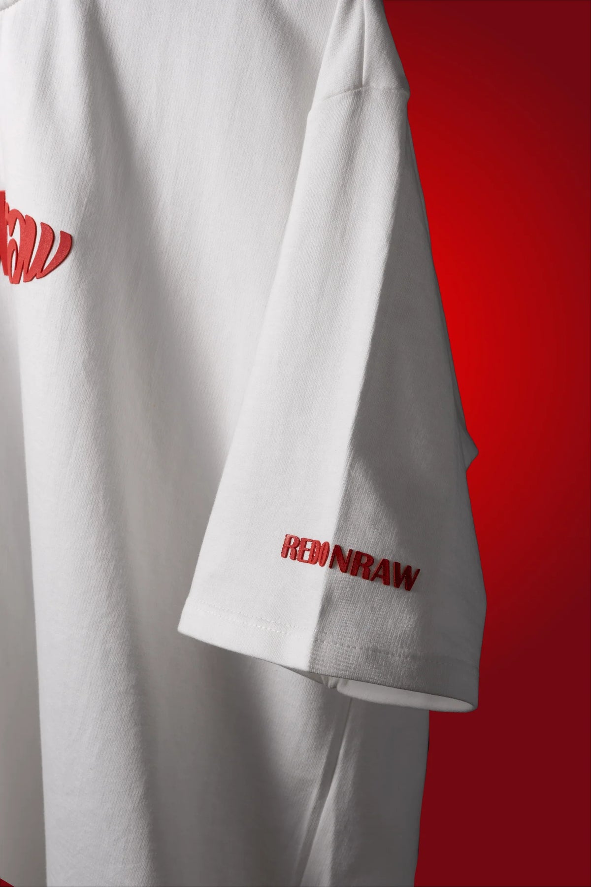 White T-shirt with red sleeve logo and partial red chest graphic.