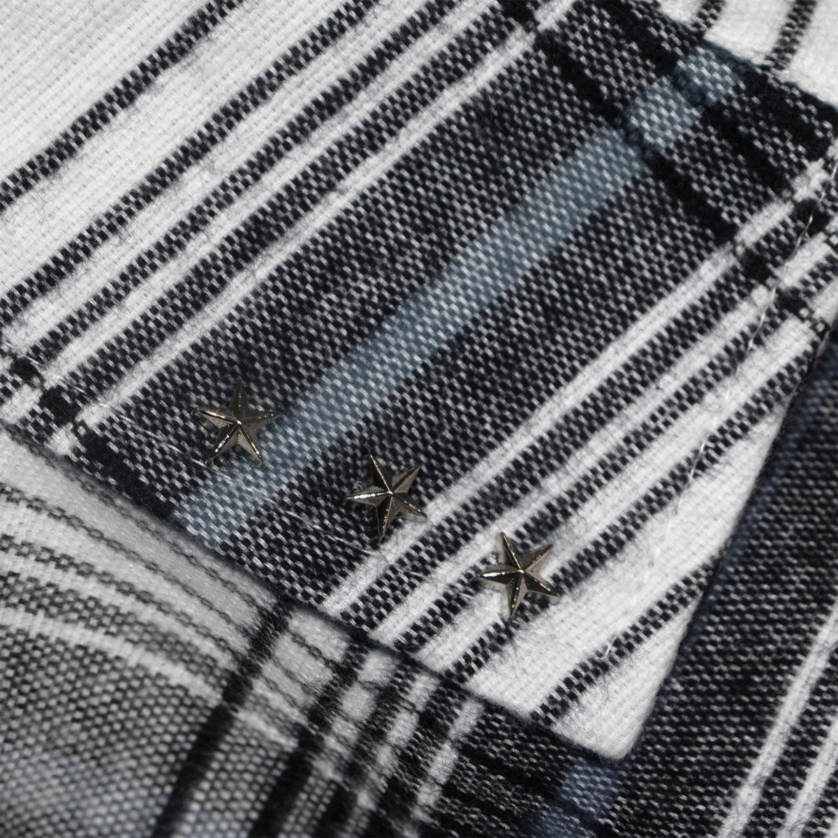 Plaid button detail with small star-shaped buttons on white and dark fabric