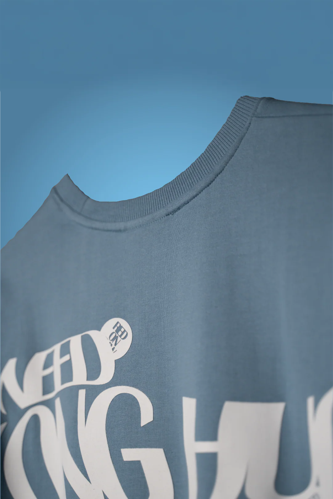 Light blue crew-neck T-shirt with large white typography graphic on chest