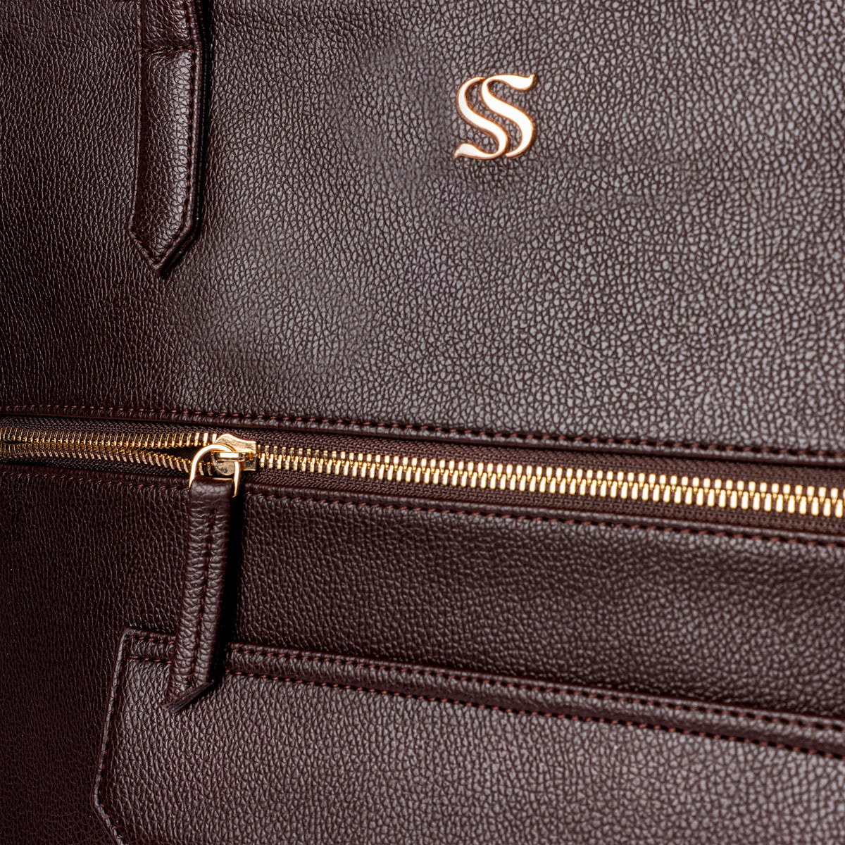 Dark brown leather tote bag zipper and gold logo emblem detail