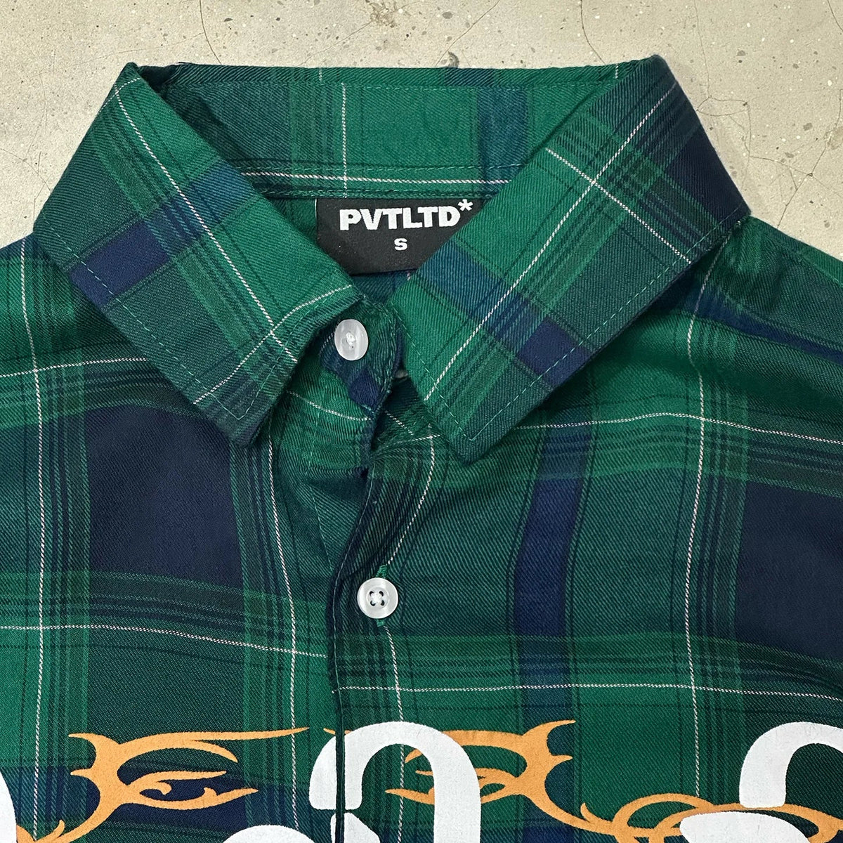 Green plaid button-up shirt with spread collar and front button placket, partial print