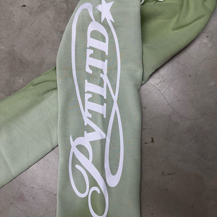 Light green track pants close-up with white vertical side logo print