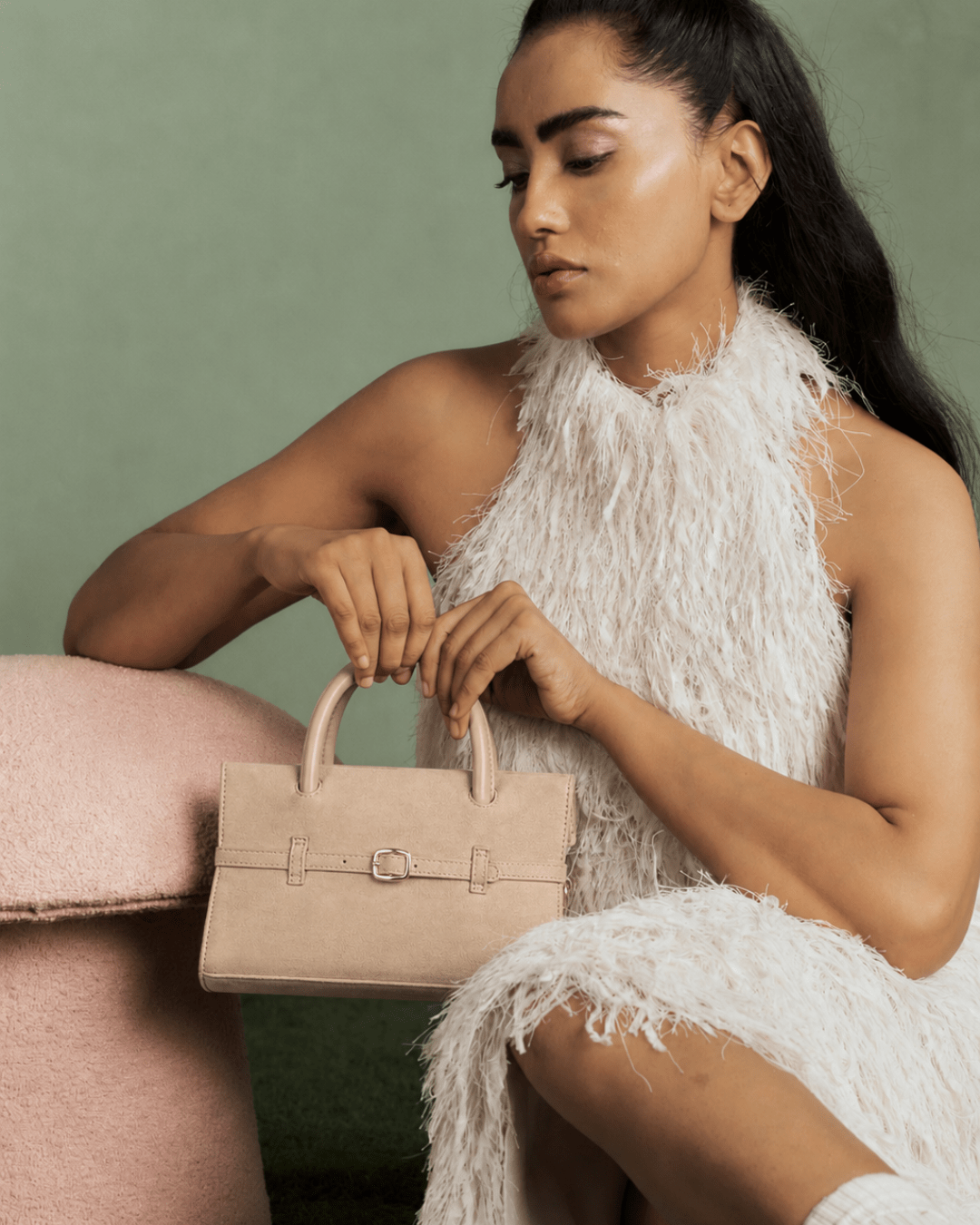 Mini cream handbag on model's arm, front buckle and structured rectangular shape