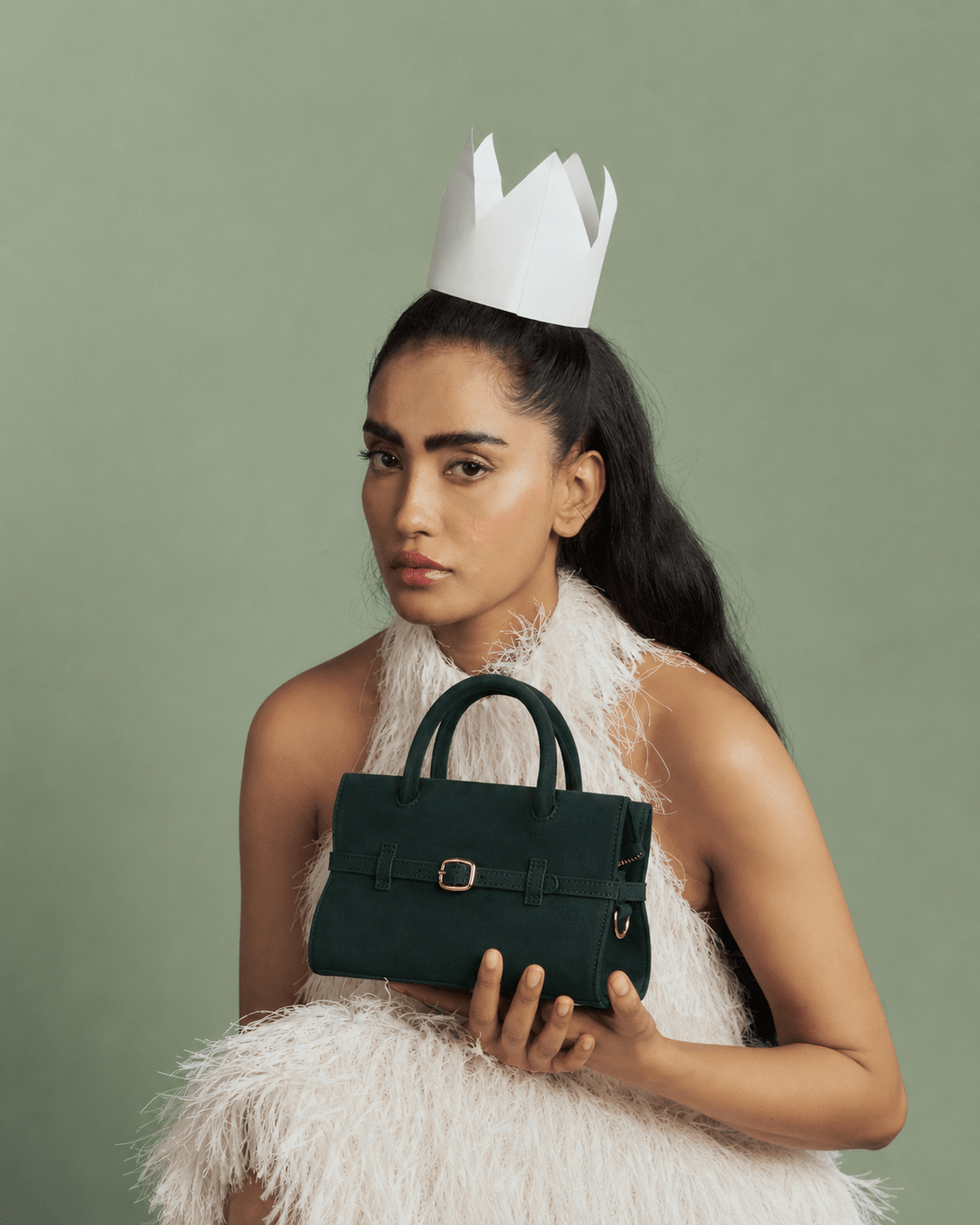 Mini emerald green handbag held in front view, top handles and front buckle