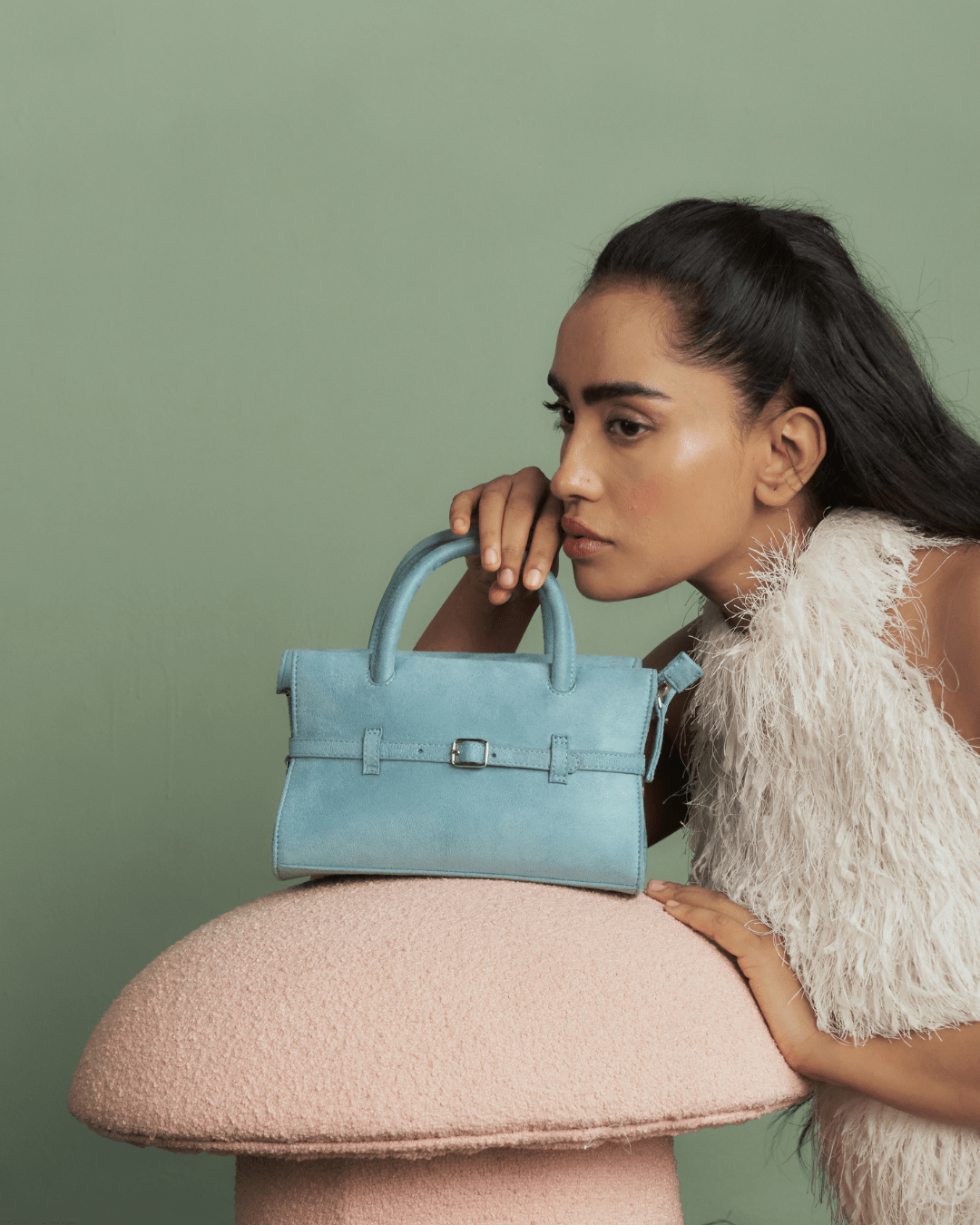 Powder blue mini handbag beside model, front buckle strap visible