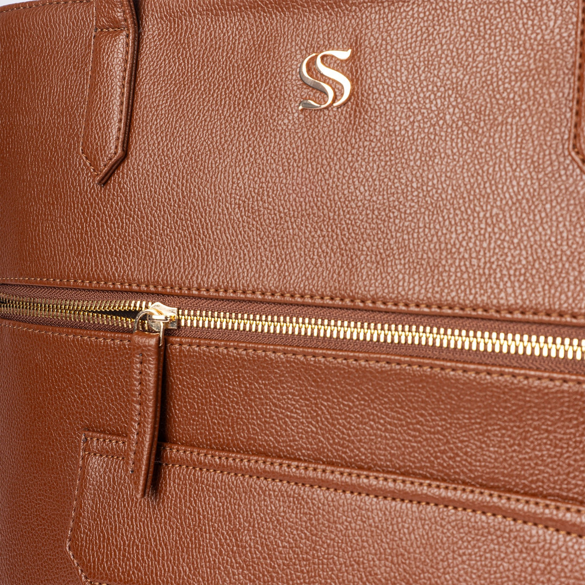 Mocha-brown tote bag close-up of gold zipper track and embossed S emblem