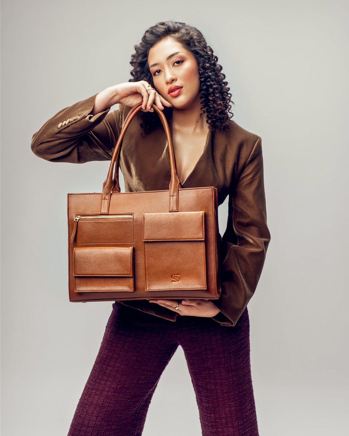 Mocha leather laptop tote with top handles, zip pockets, and embossed S emblem