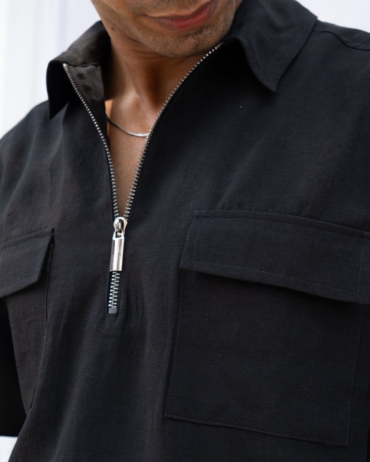 Black zip-front shirt detail with front pocket and metal zipper