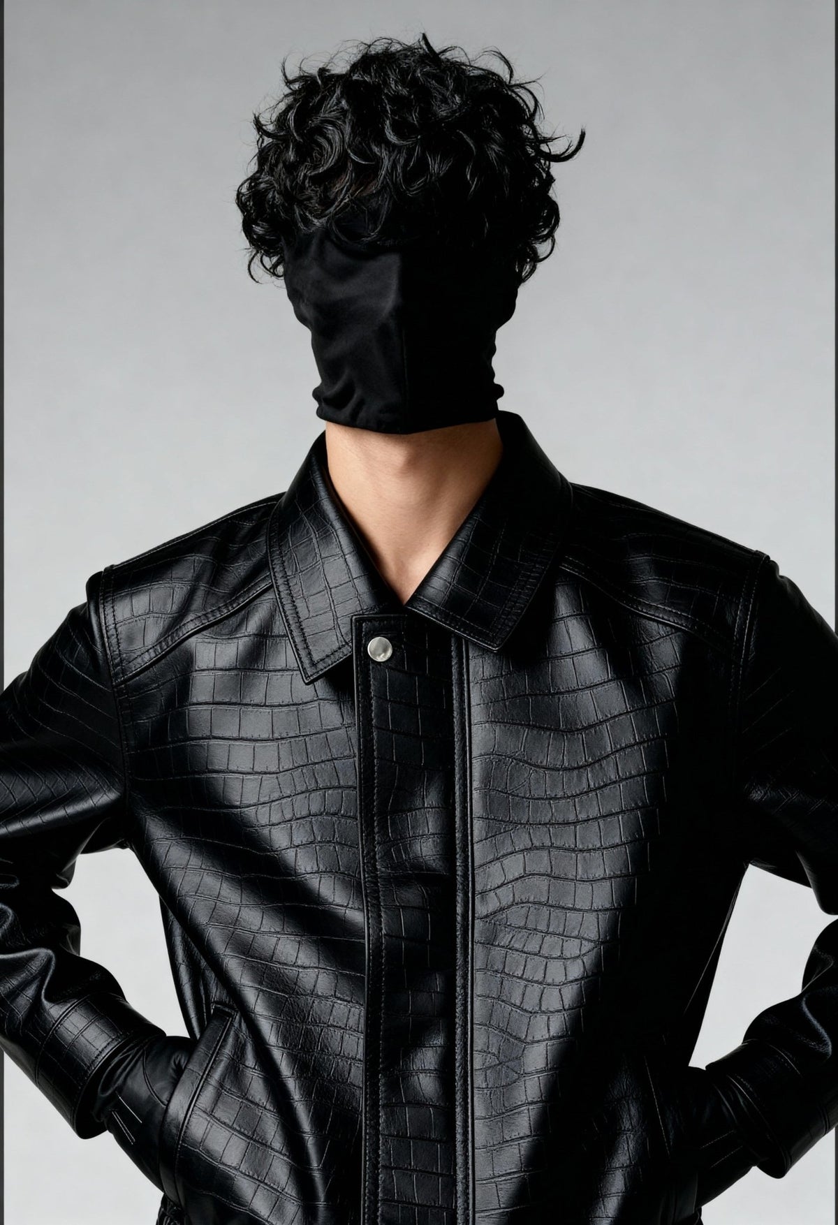 Black croc-textured leather bomber jacket close-up with snap-front placket and chest panel