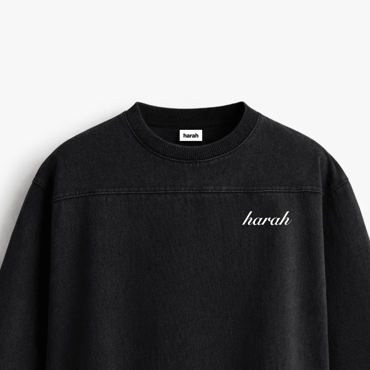 Black oversized boxy rugged T-shirt close-up with harah script logo on chest