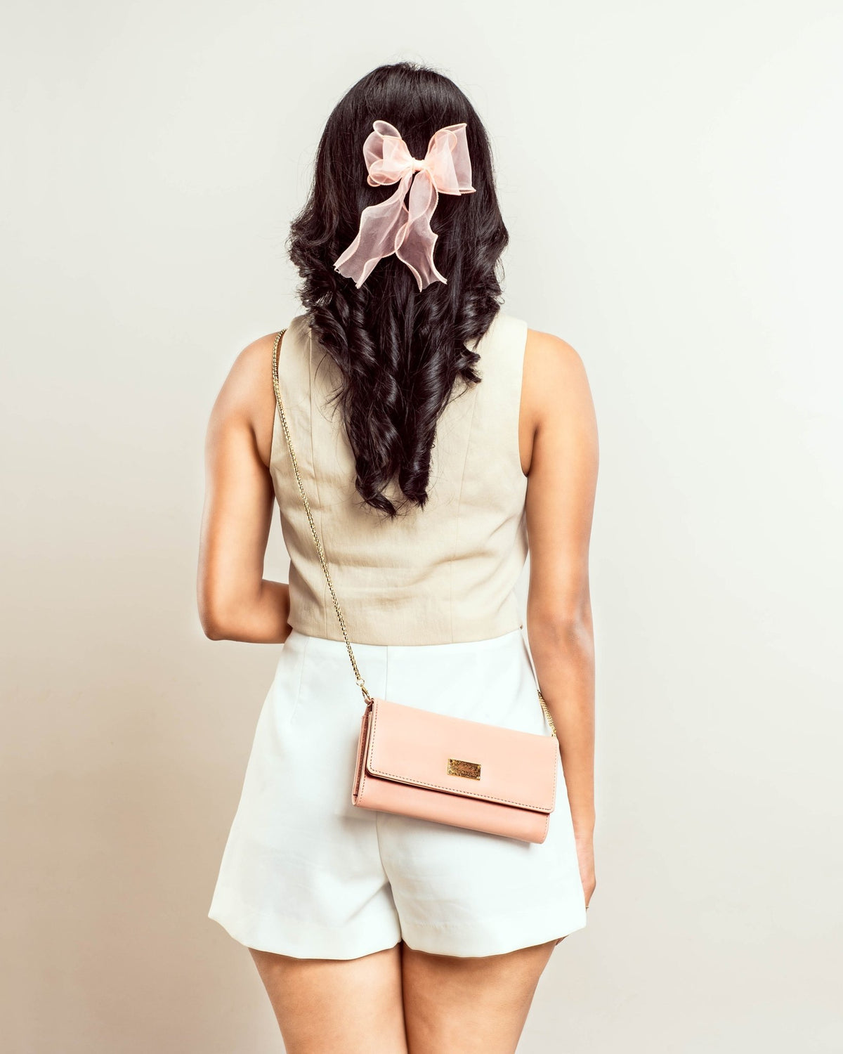Peach crossbody clutch wallet worn on shoulder with gold chain