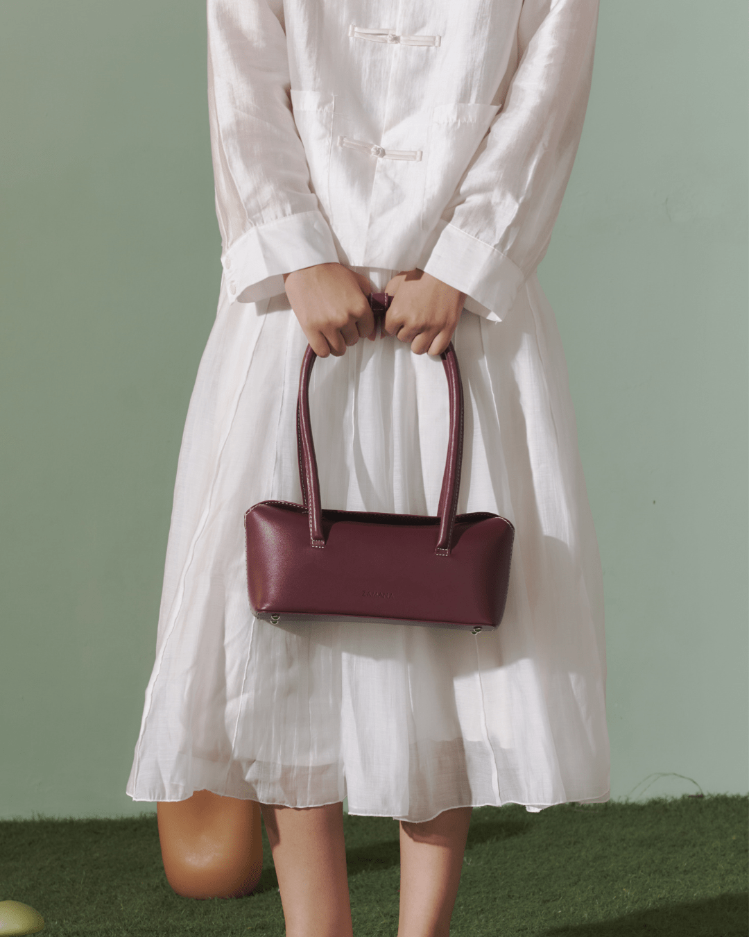Burgundy leather-look top-handle bag held by straps with visible logo front