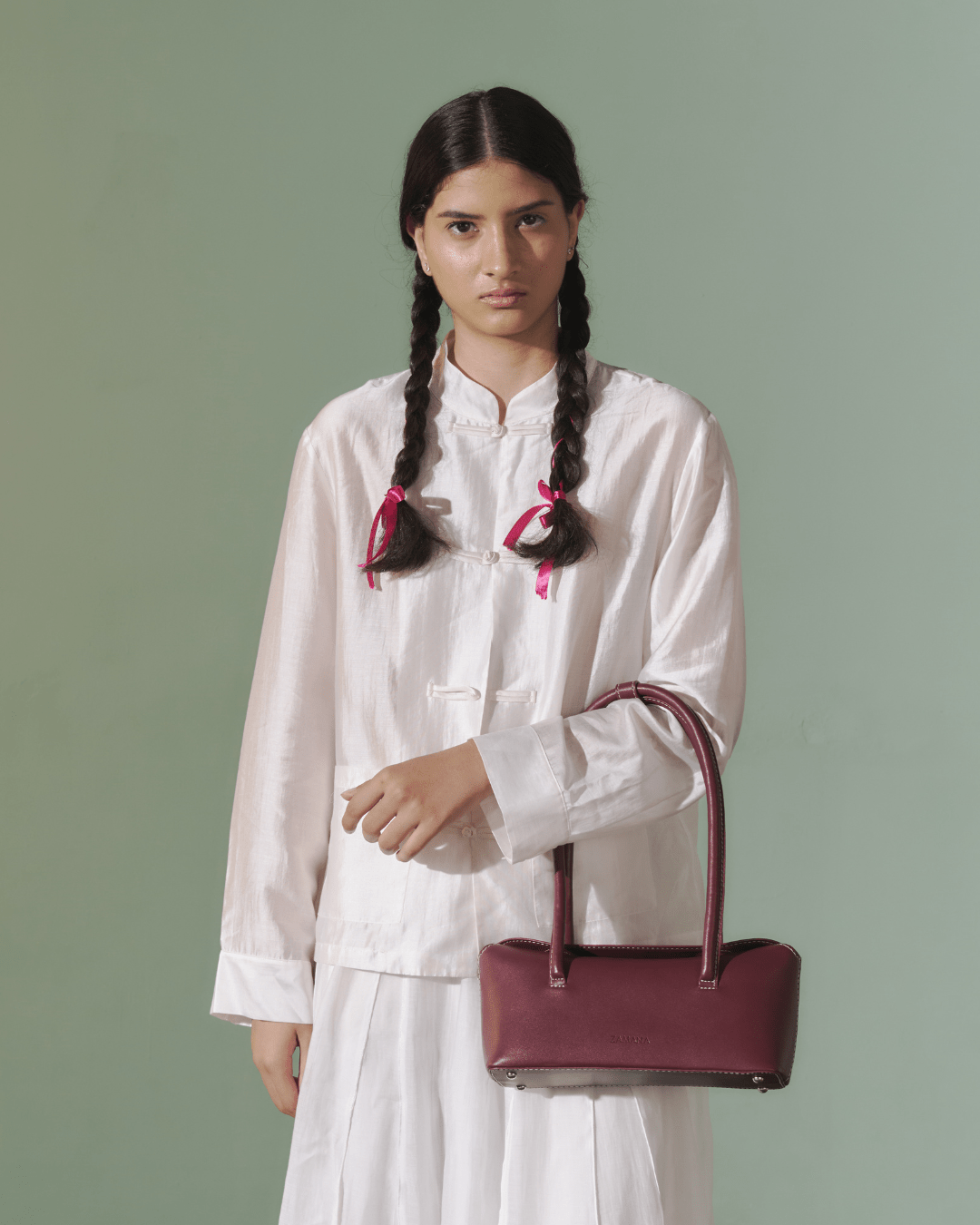 Burgundy leather-look top-handle bag with long handles worn over a white dress