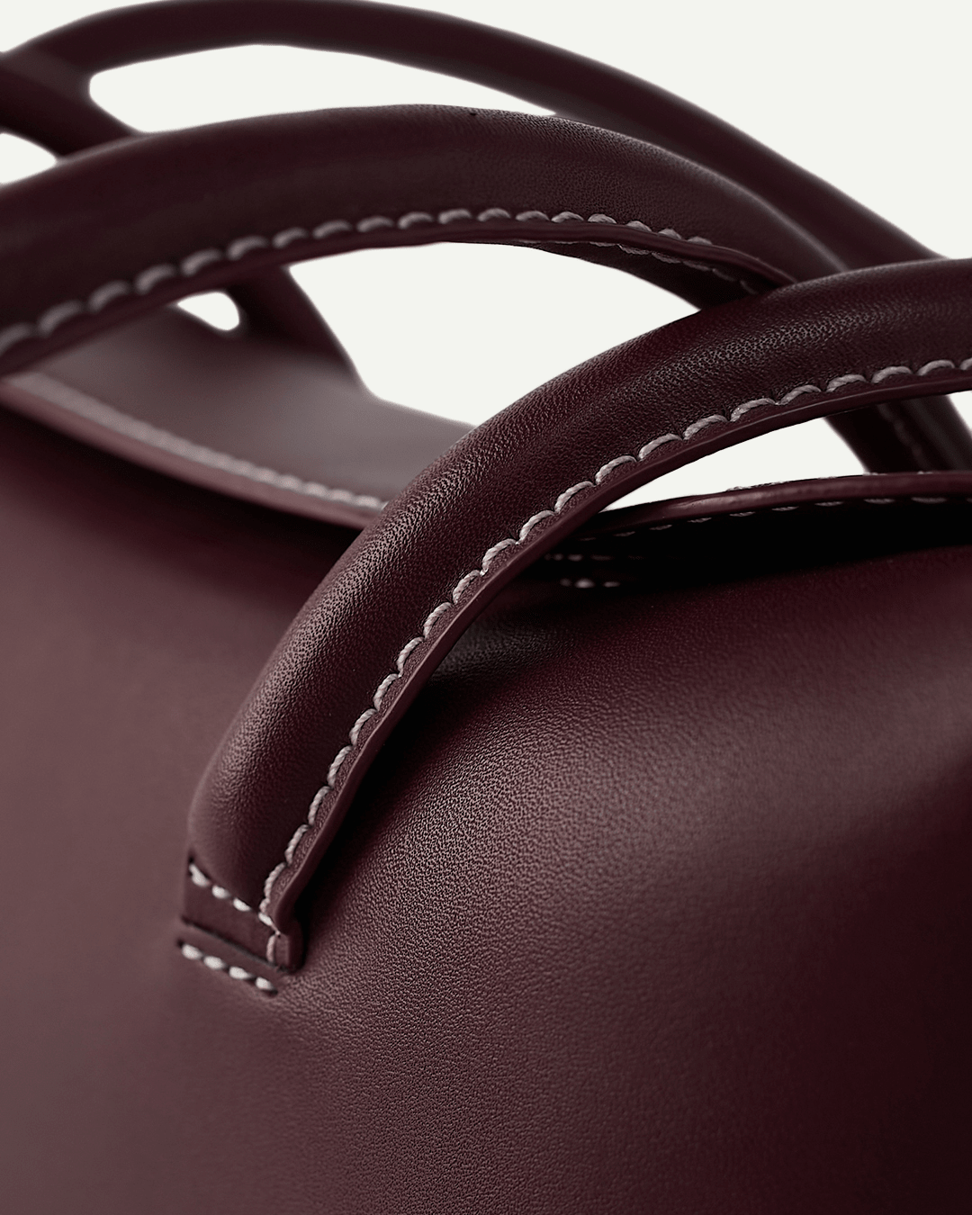 Close-up of burgundy bag handles with contrast edge stitching
