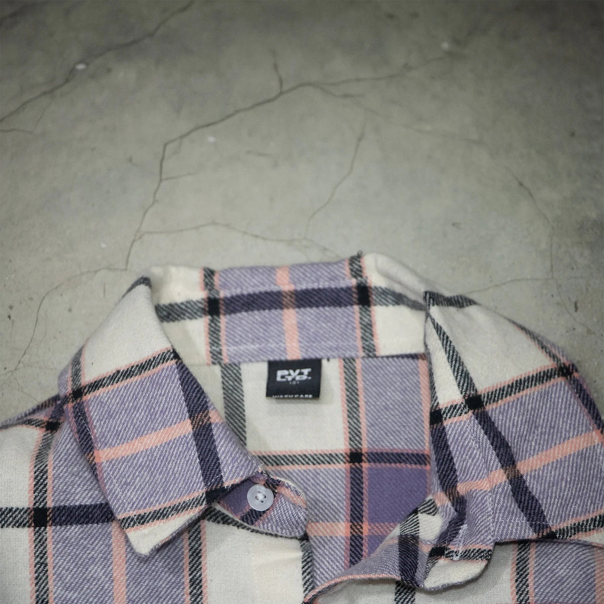 Close-up of purple, white, and orange plaid shirt collar with branded tag