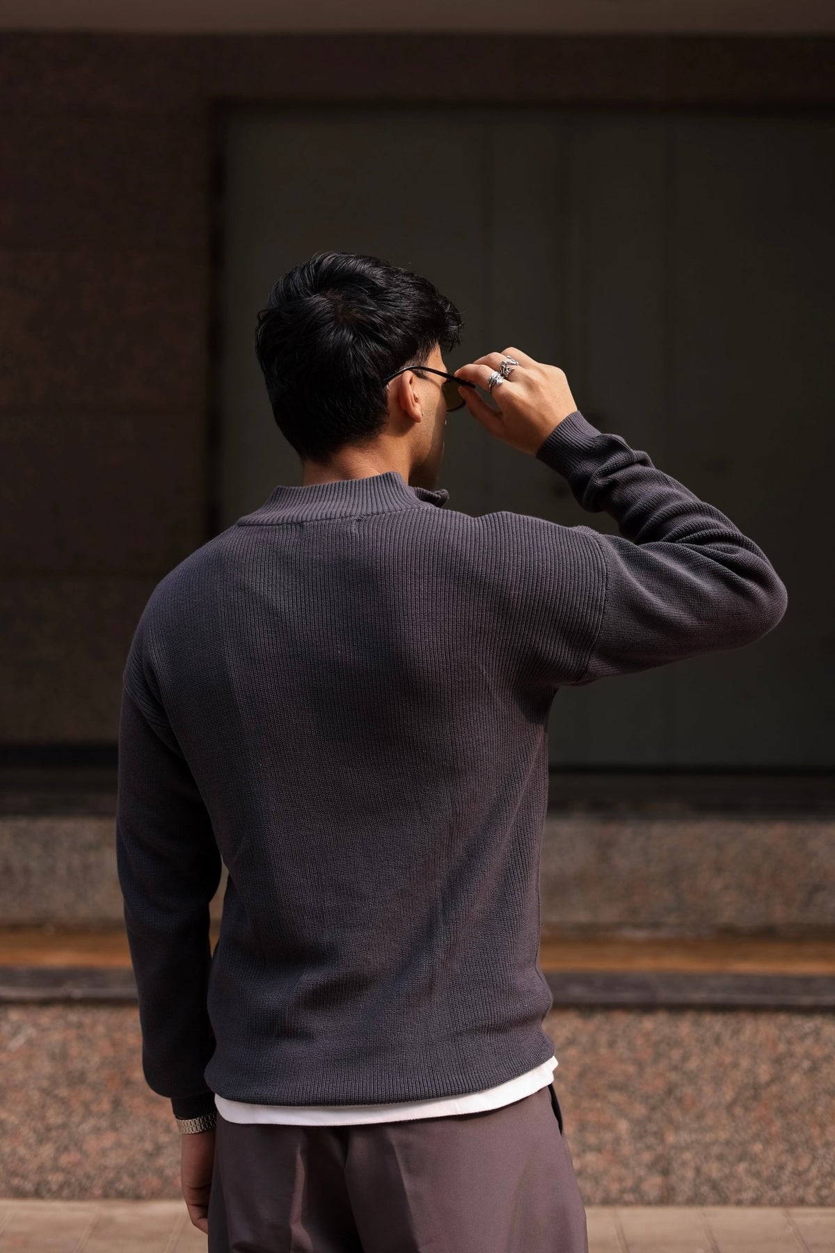 Charcoal quarter-zip knit sweater from the back, long sleeves with ribbed cuffs.