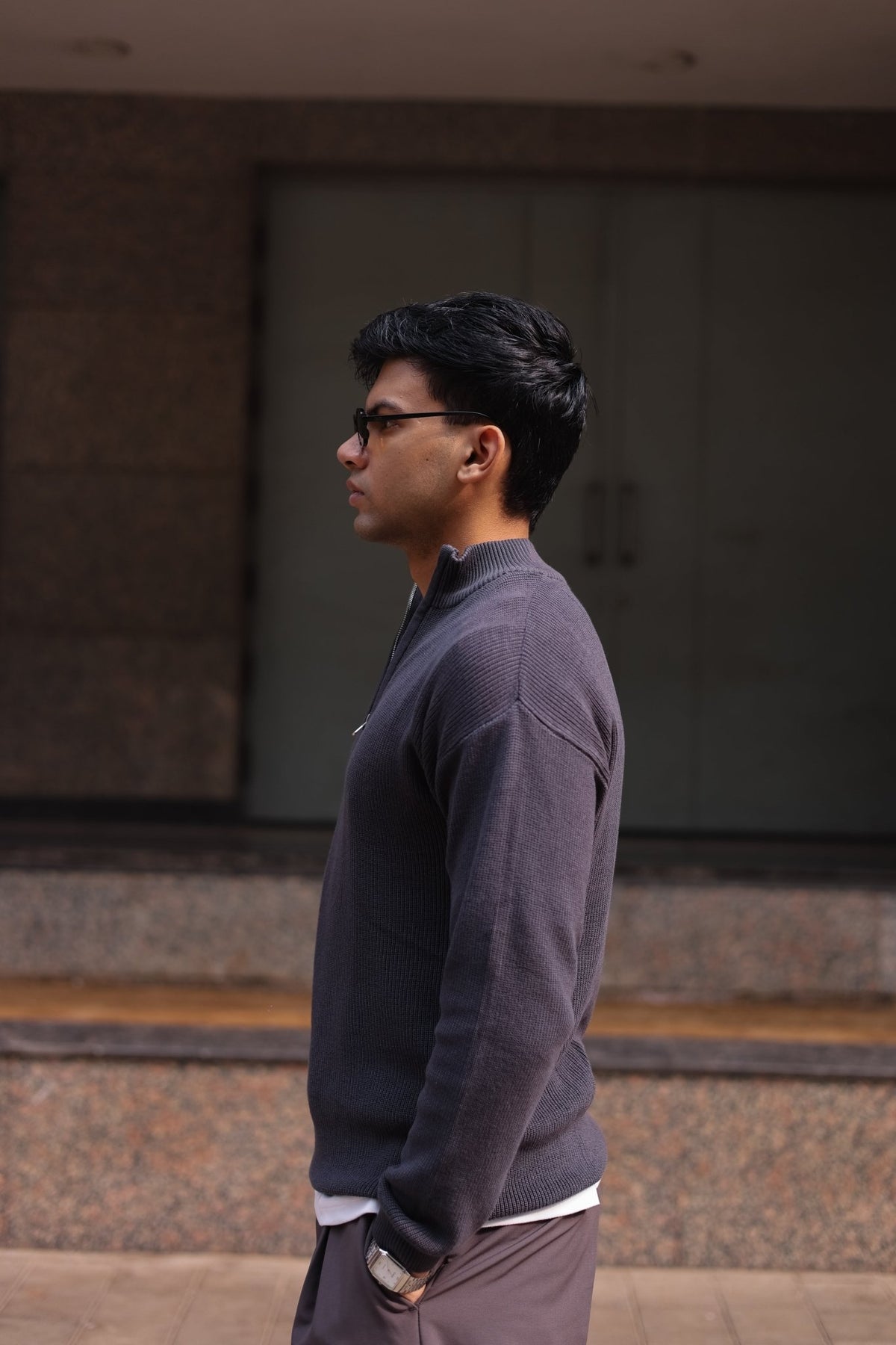 Charcoal quarter-zip knit sweater with long sleeves and ribbed hem, side view.