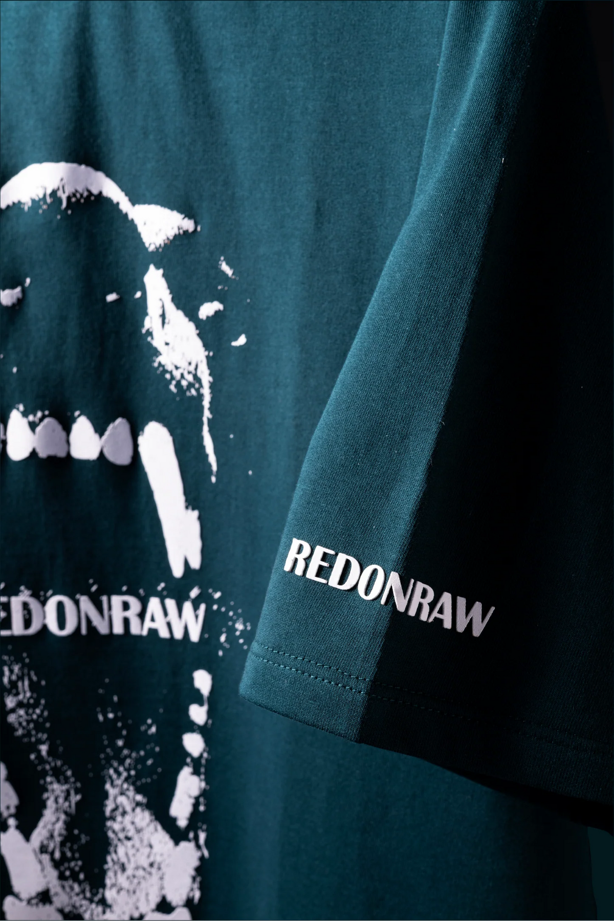 Sea green T-shirt sleeve with REDONRAW wordmark and partial graphic