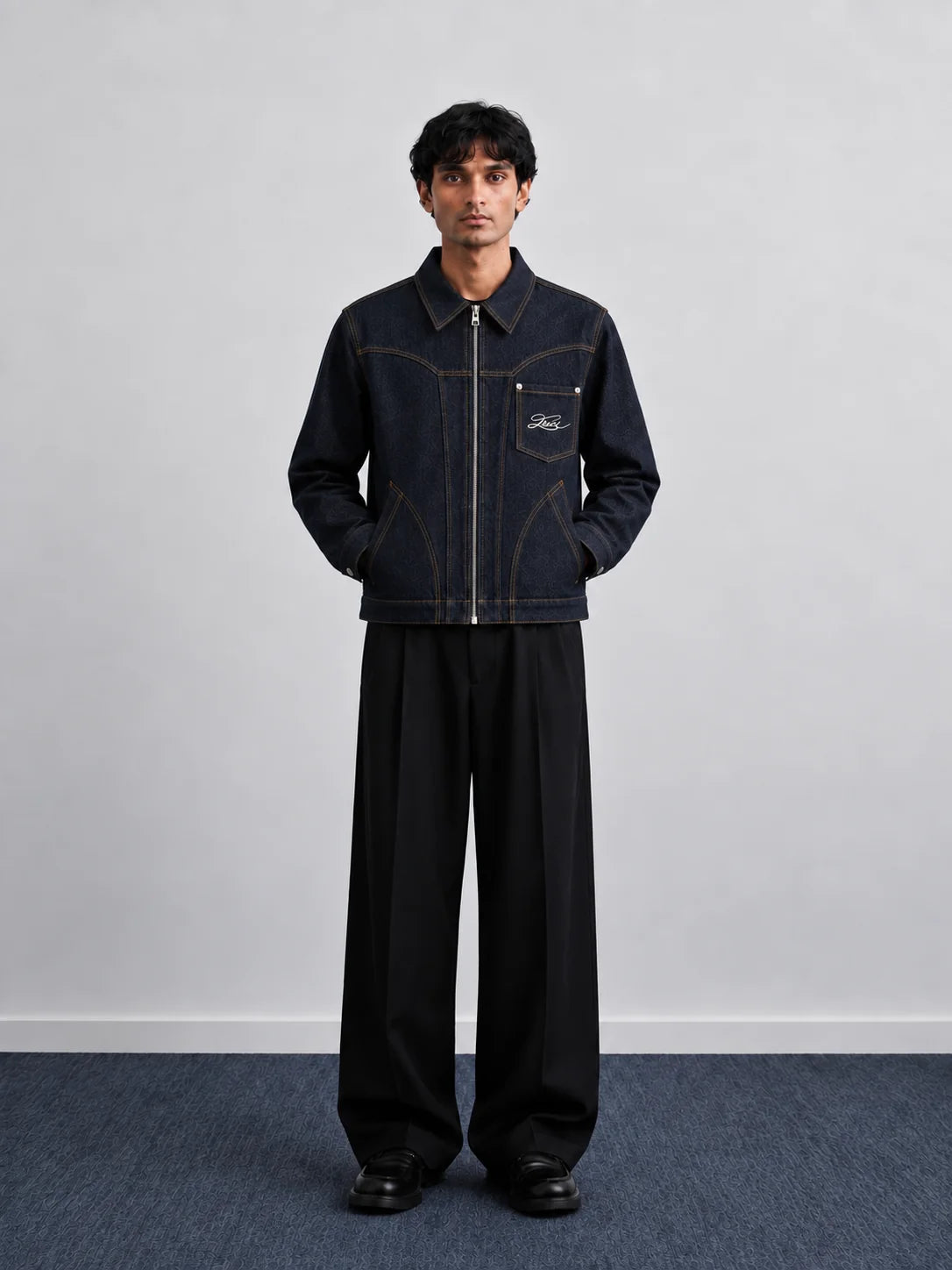 Indigo denim jacket with contrast stitching and button front, worn with black wide-leg pants