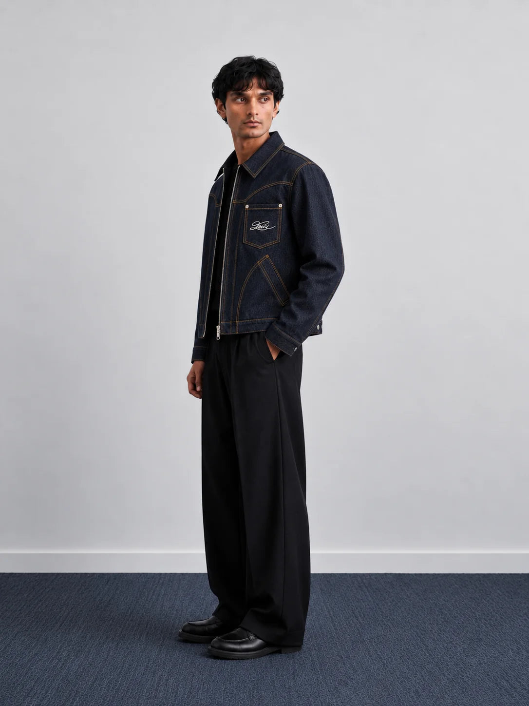 Indigo denim jacket with button front and contrast stitching, worn with dark trousers