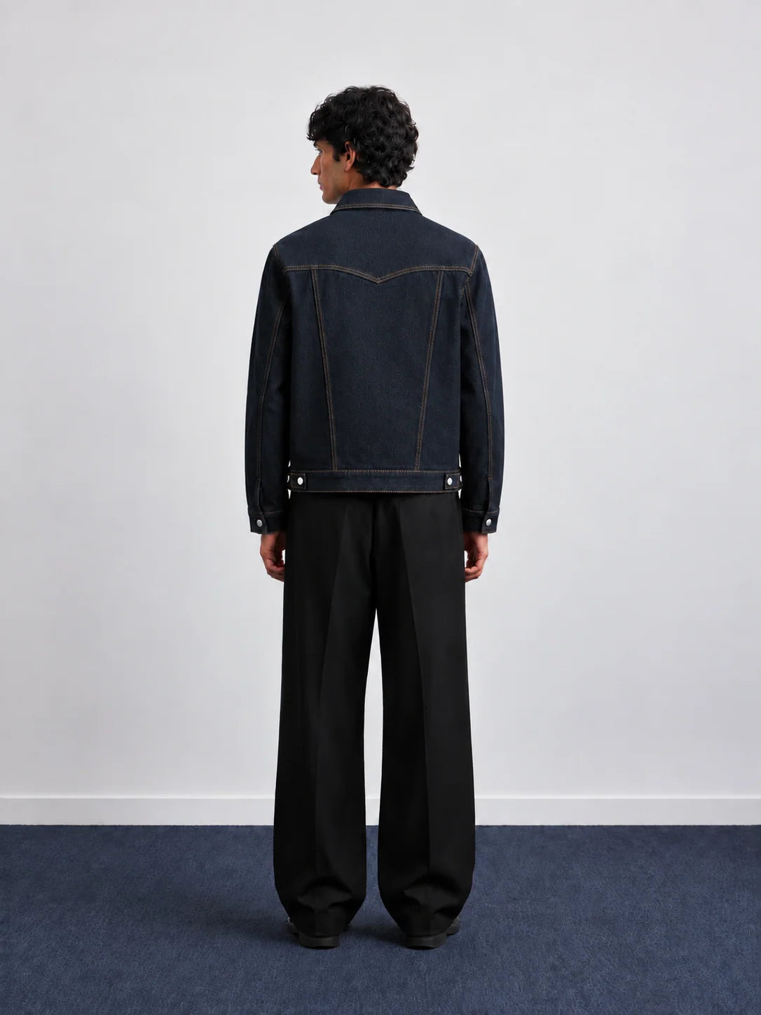 Dark blue denim jacket, back view, with contrast panel stitching and button cuffs