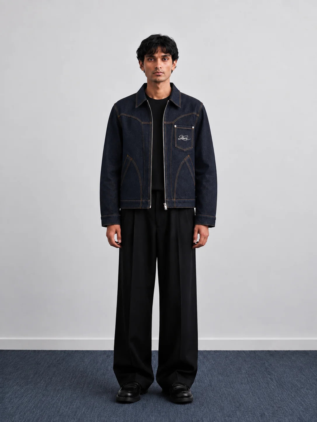 Indigo denim jacket with pointed collar, chest patch pockets, and contrast piping