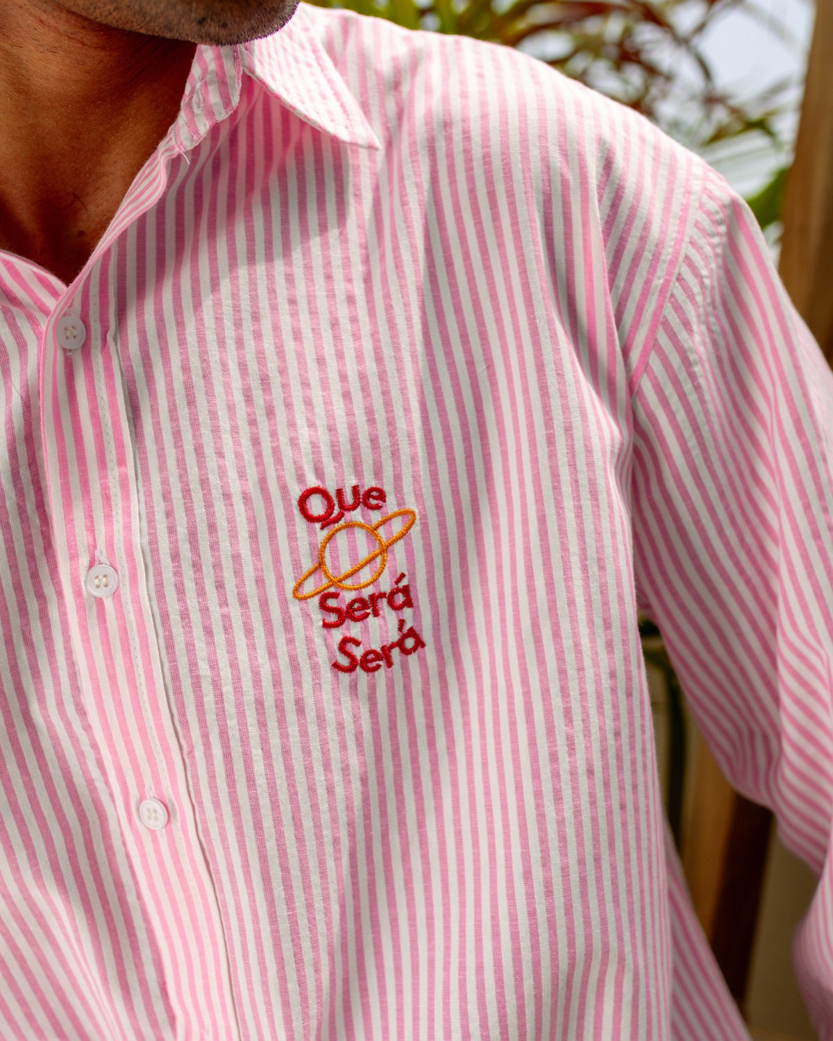 Pink striped seersucker shirt close-up, orange embroidered logo on chest