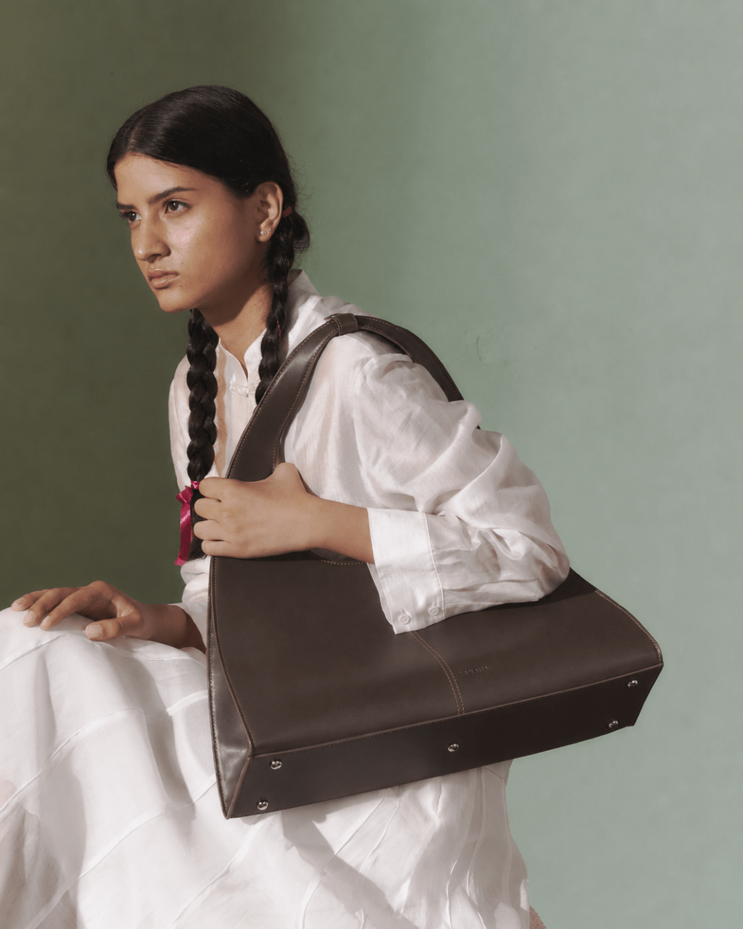Dark brown leather-look triangular tote bag carried over the shoulder with top handle