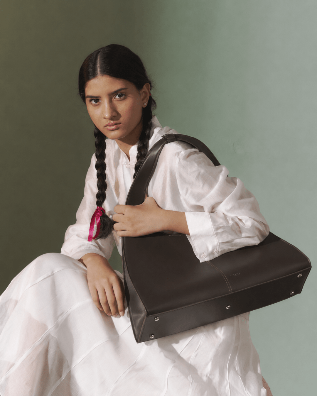 Dark brown leather-look triangular tote bag held in front with top handle