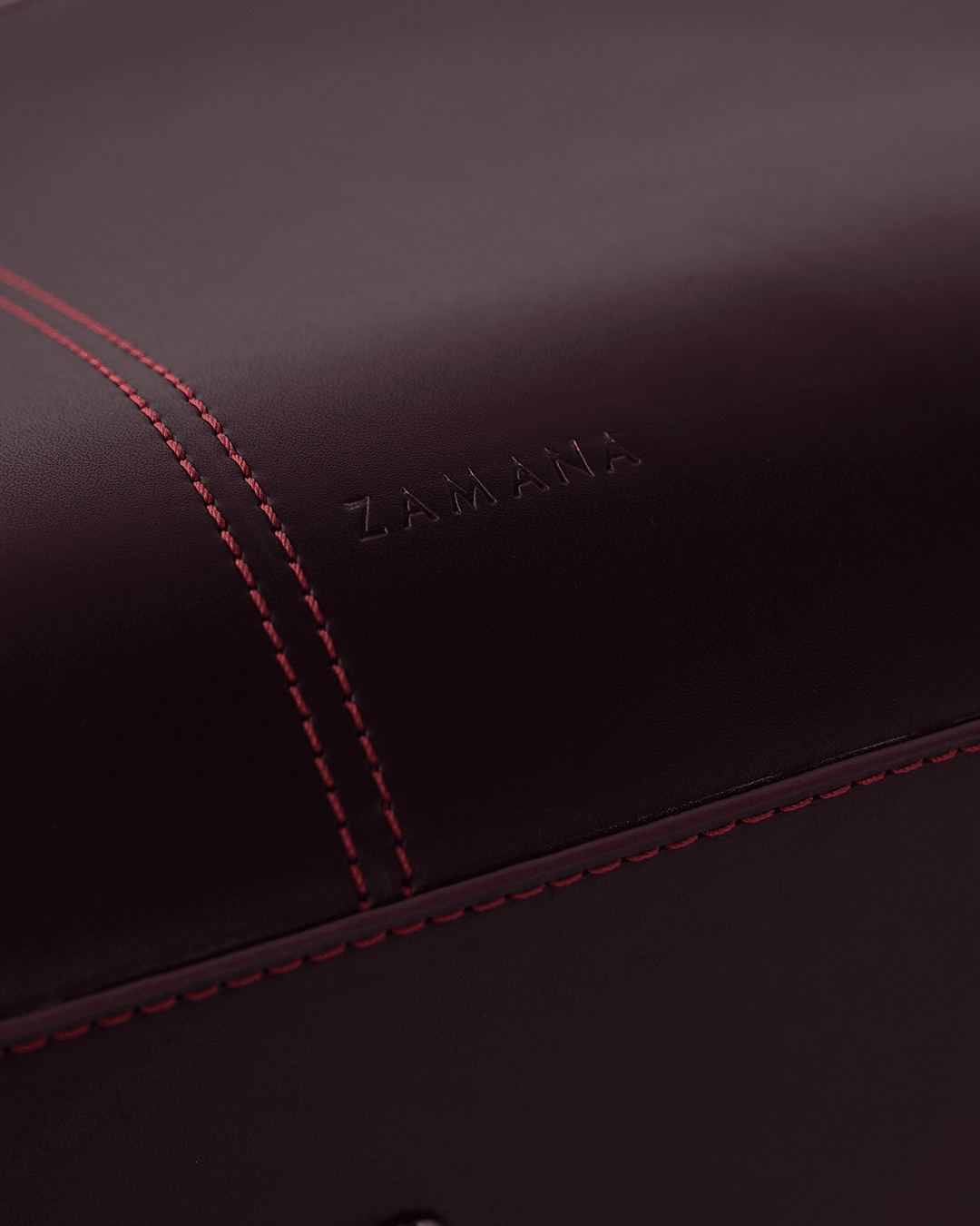 Burgundy leather tote bag with embossed ZAMANI logo and red contrast stitching