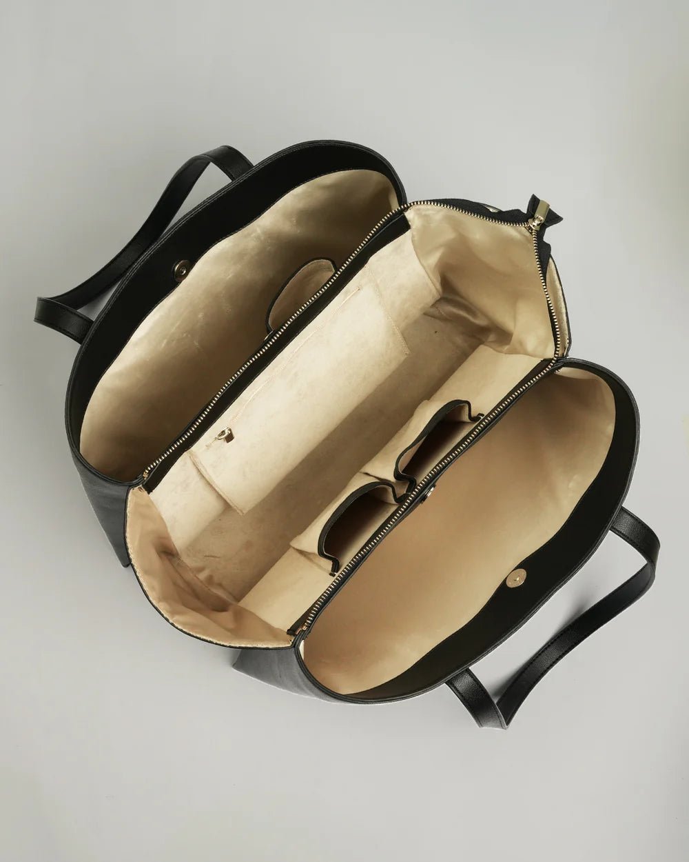 Open black tote bag showing beige fabric lining and zippered top, side view