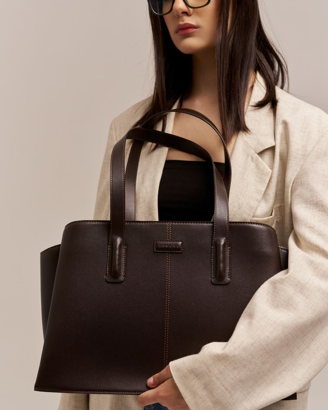 Dark brown leather tote bag with two top handles and front stitched detail