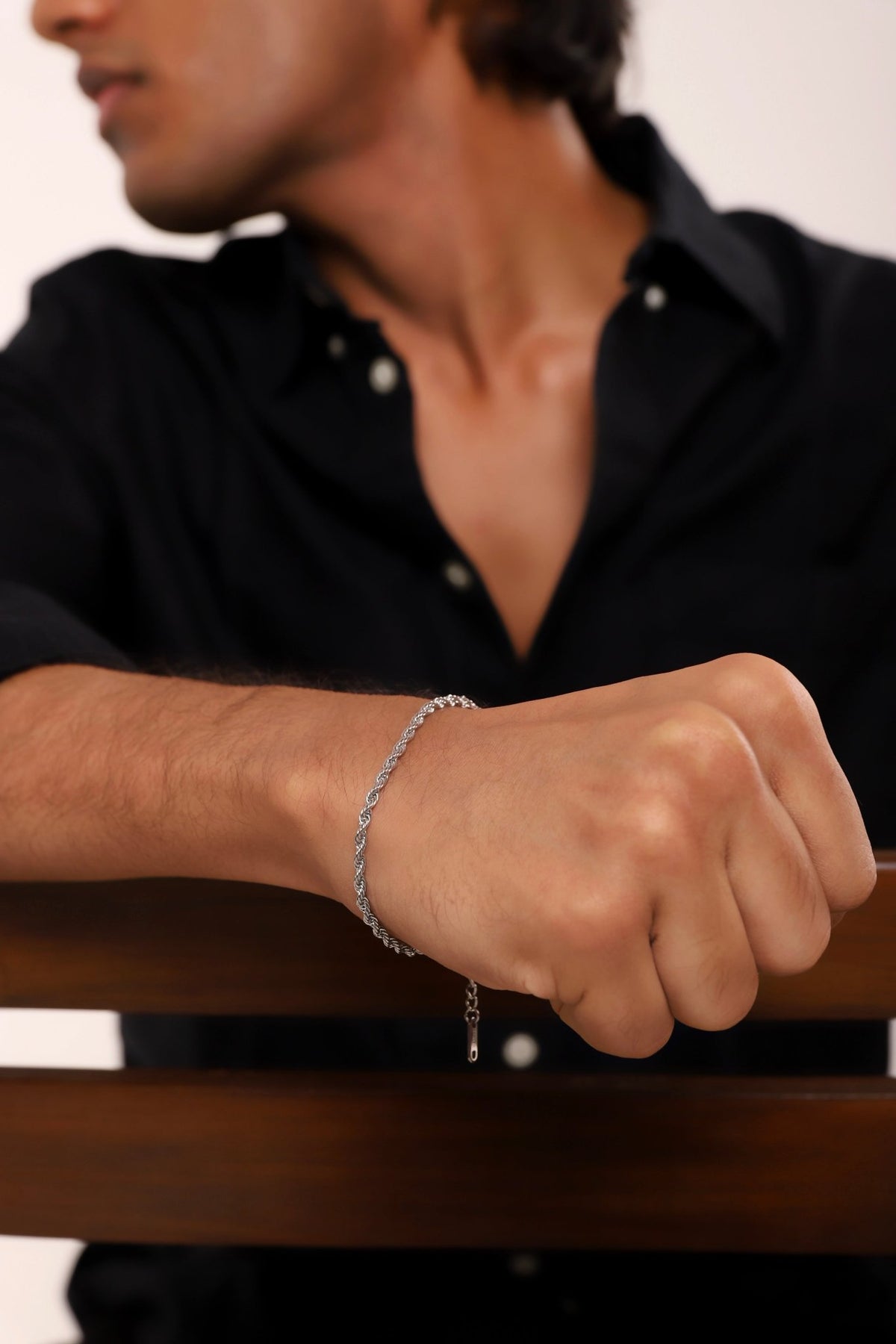 Silver rope chain bracelet worn with clasp and vertical charm detail