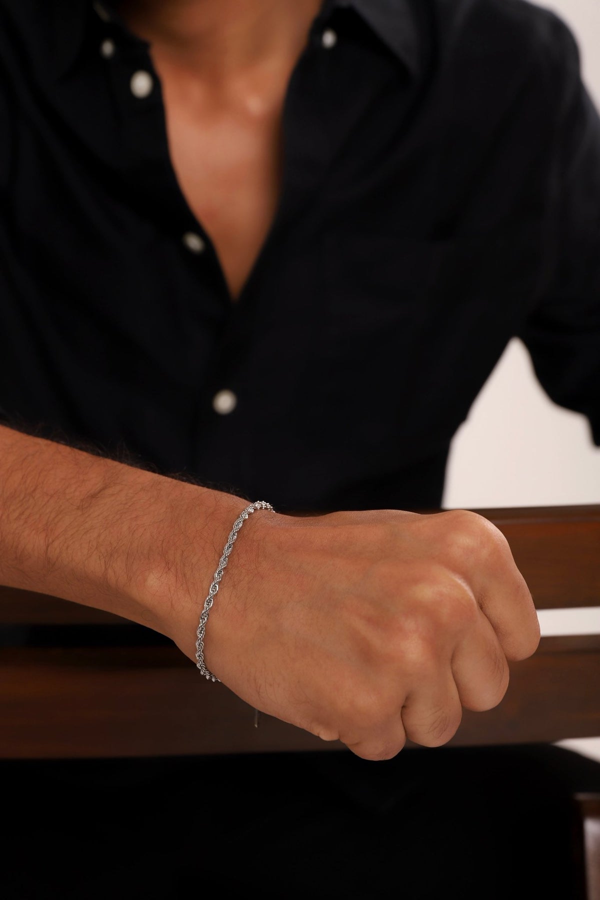 Silver rope chain bracelet on wrist with dangling charm