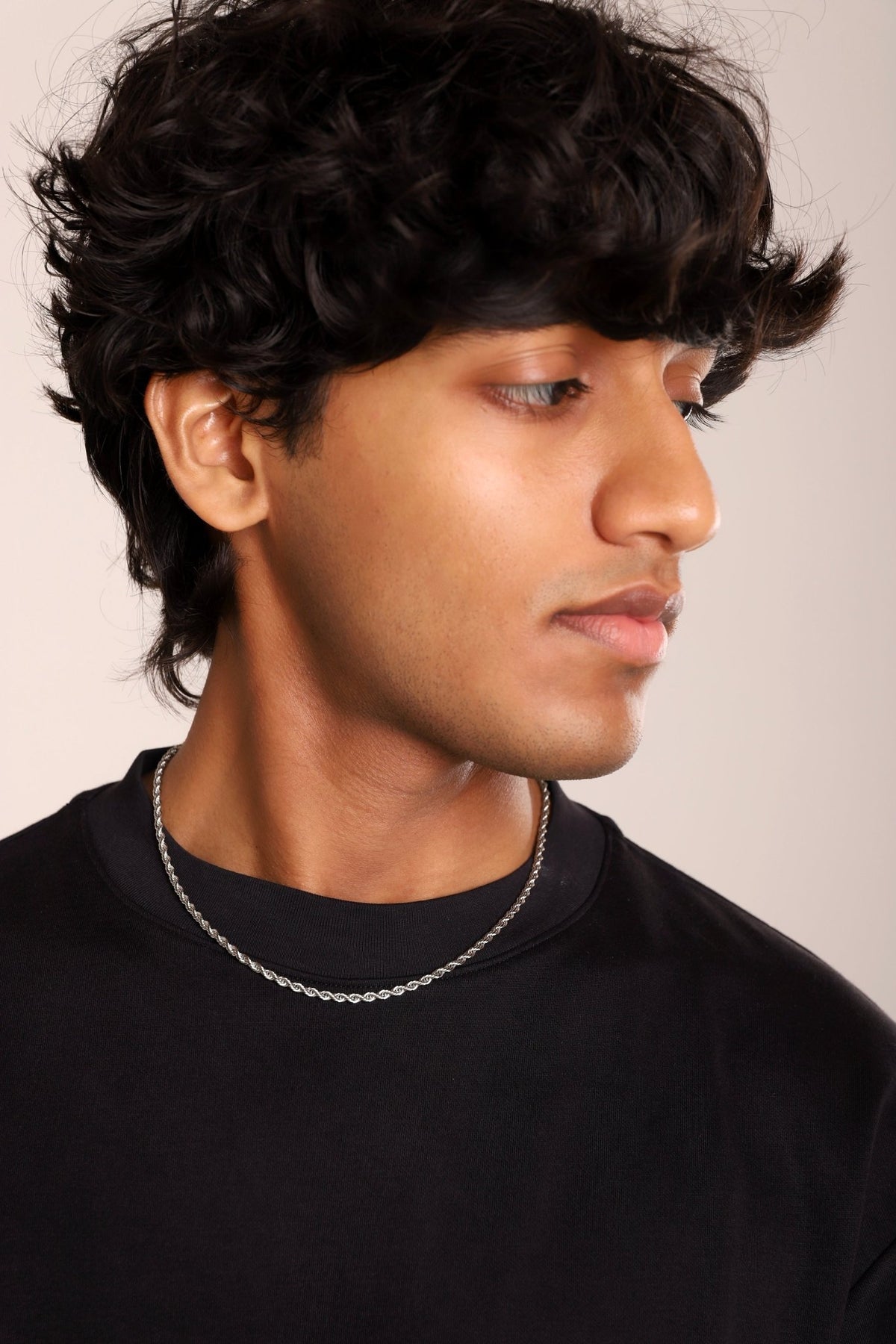 Rope chain necklace on a black crew-neck shirt, twisted rope-link pattern