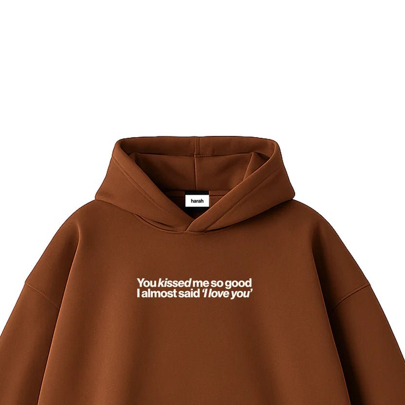 Brown hoodie with drawstring hood and front chest graphic text, close-up label.